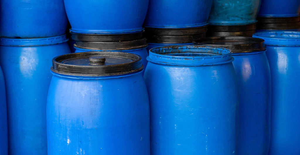 Fûts métalliques de 60 litres étiquetés pour le stockage d'huiles alimentaires usagées dans un local technique propre d'arrière-cuisine professionnelle